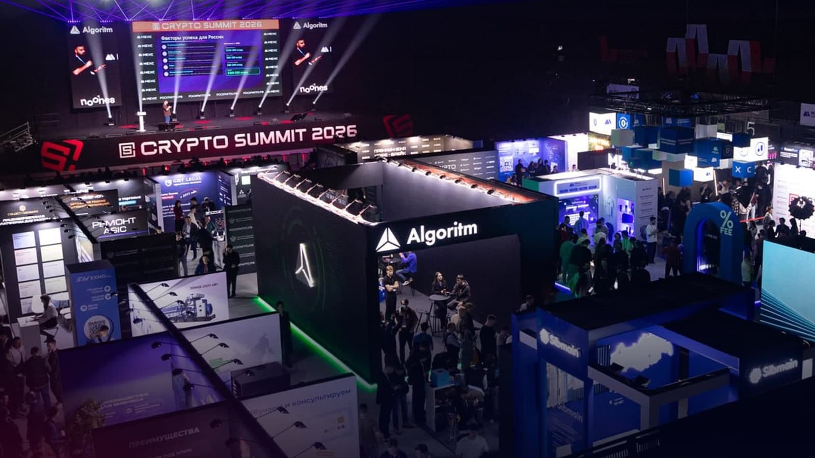 Зал IX Crypto Summit 2026 в МТС Live Холле: сцена с экранами и экспозона криптокомпаний, вид сверху